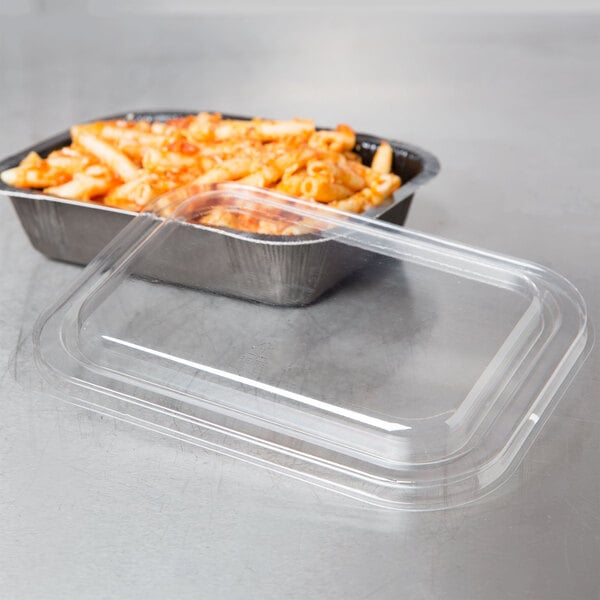 A tray of pasta with a Solut clear plastic lid on a table.