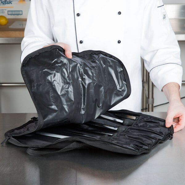 A chef holding a black bag of Victorinox knives.