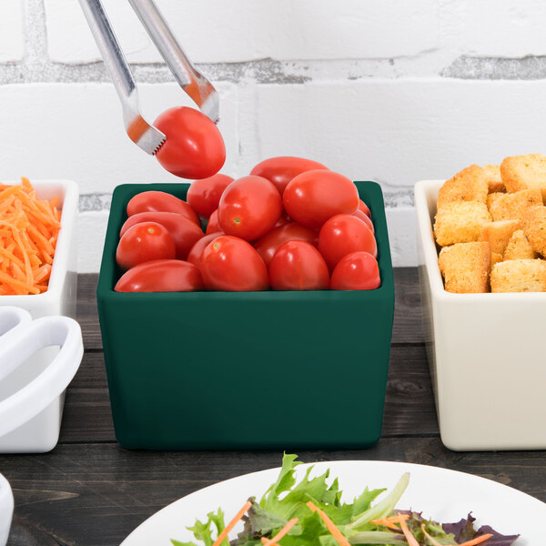 A Tablecraft hunter green bowl filled with tomatoes and croutons on a table in a salad bar.