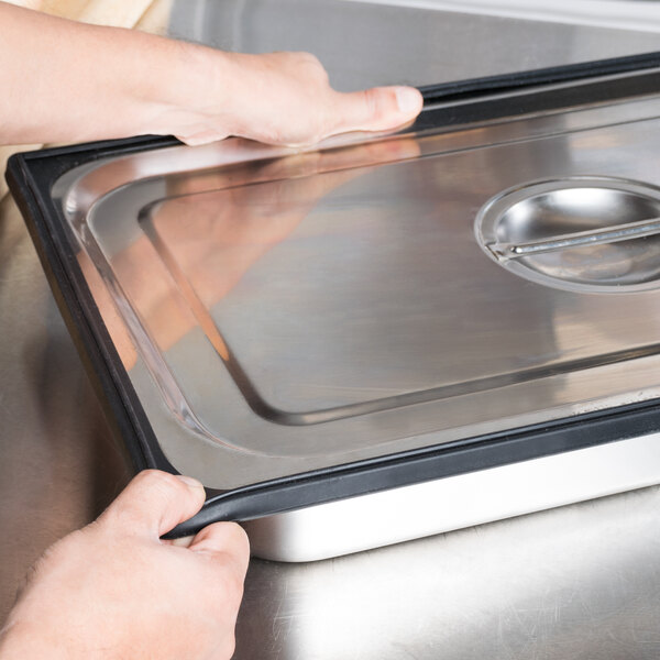 A person holding a black Vollrath silicone band on a metal tray.