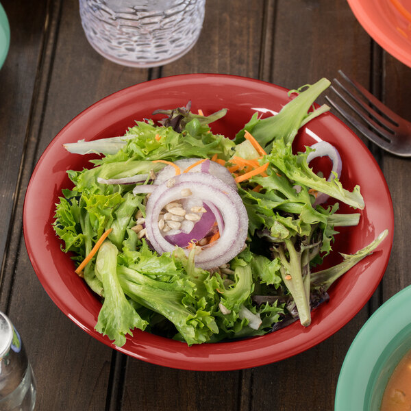 A red GET Diamond Harvest melamine bowl filled with salad on a table.