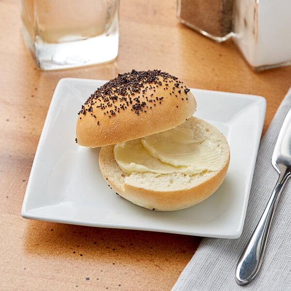 A bun with butter on top on an Acopa bright white square porcelain plate.