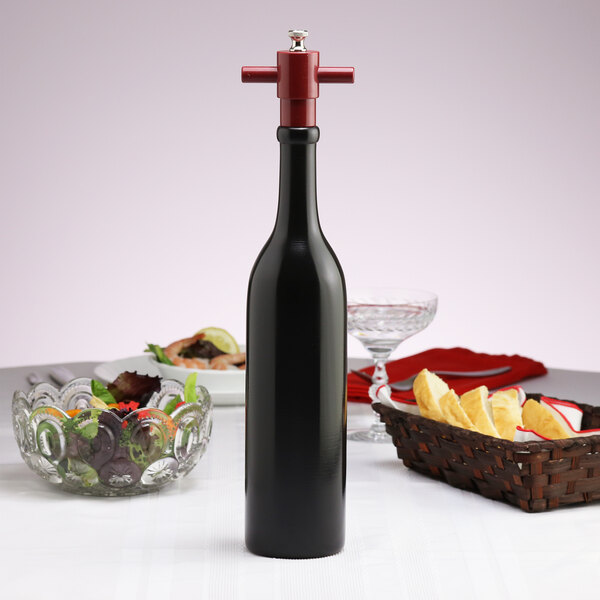 A Chef Specialties Chateau wine bottle pepper mill on a table next to a bowl of food.