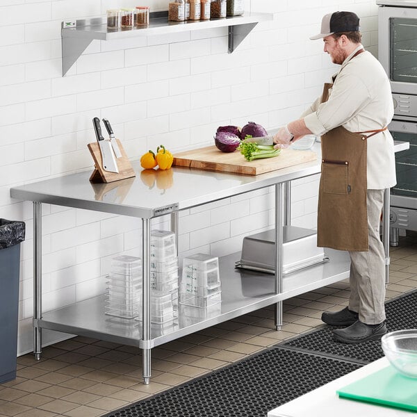 A man in a brown apron cutting vegetables on a Regency stainless steel work table with undershelf.