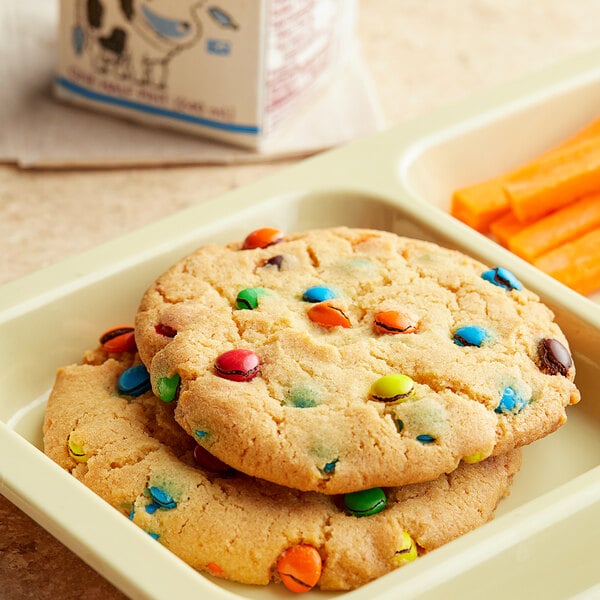A tray of cookies and carrot sticks with M&M's Milk Chocolate Mini Baking Bits on top.