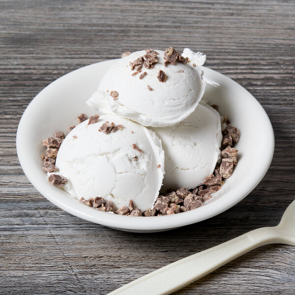 A white bowl of ice cream with Nestle Crunch topping and a spoon.