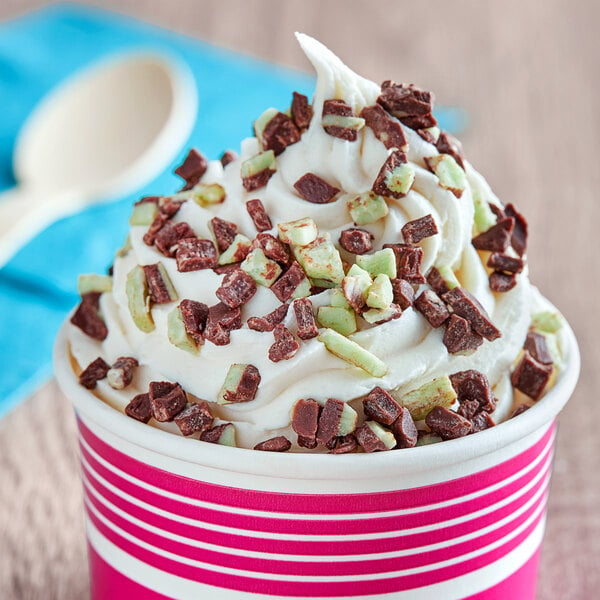 A cup of ice cream topped with Andes Mint pieces and chocolate chips.