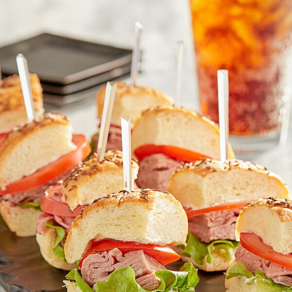 A tray of sandwiches with a Royal Paper clear plastic prism food pick in a sandwich.