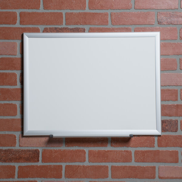 A Universal deluxe white melamine dry erase board on a brick wall.