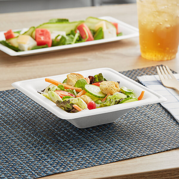 A salad in a white EcoChoice compostable sugarcane bowl on a placemat.
