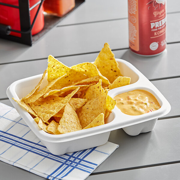 A white EcoChoice compostable bagasse tray with chips and yellow sauce on a table.