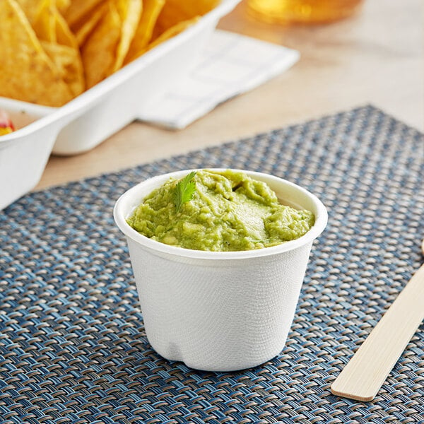 A cup of guacamole with chips served in an EcoChoice Bagasse Portion Cup.
