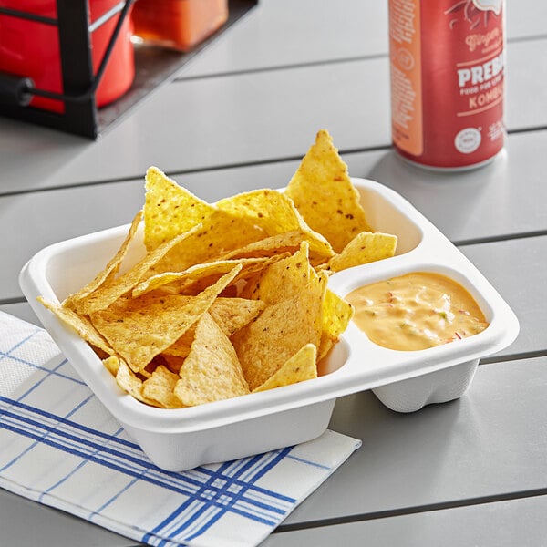 An EcoChoice bagasse food tray with chips and yellow sauce on a table.
