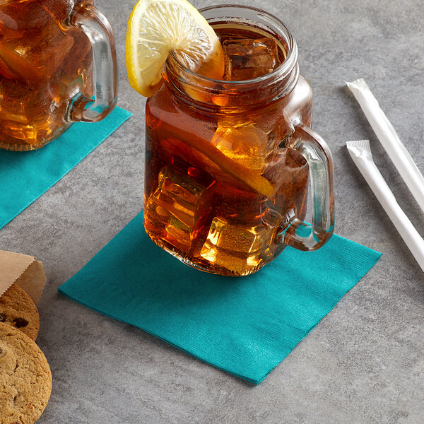 A glass mug with a Choice teal napkin with a lemon slice on the rim filled with iced tea.