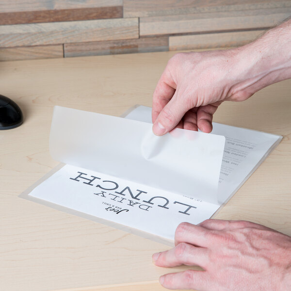 A hand using a Universal clear laminating pouch to laminate a piece of paper.