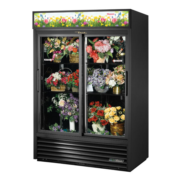 A True black refrigerated floral case with flowers in it.