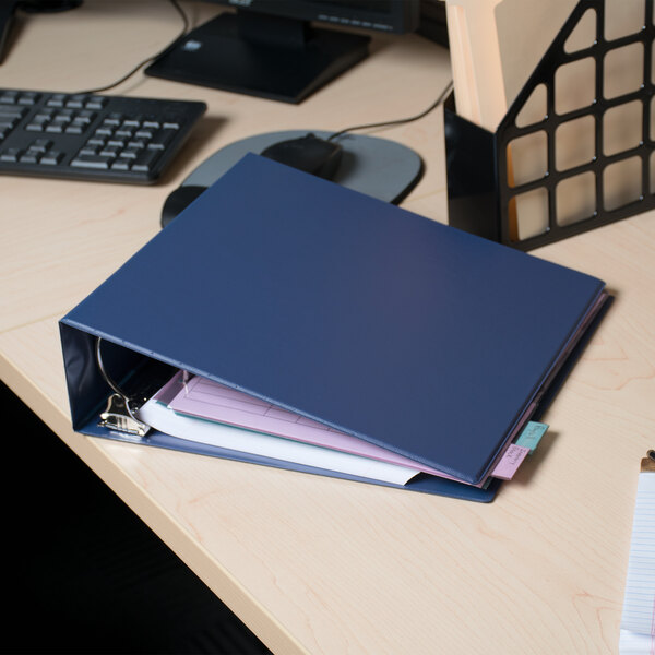 A blue Universal economy non-stick binder with papers on a desk.