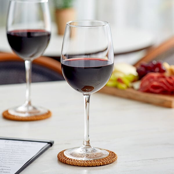 A close-up of a glass of red wine on a table with food.