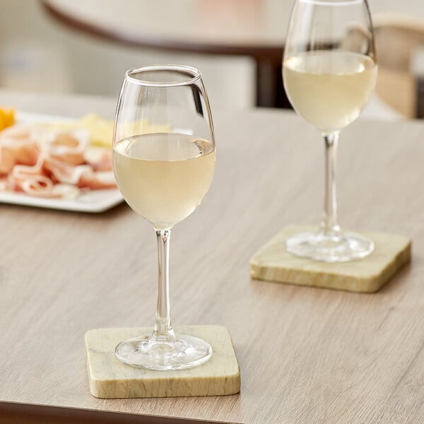 Two Acopa Select Blanc wine glasses of white wine on a table.