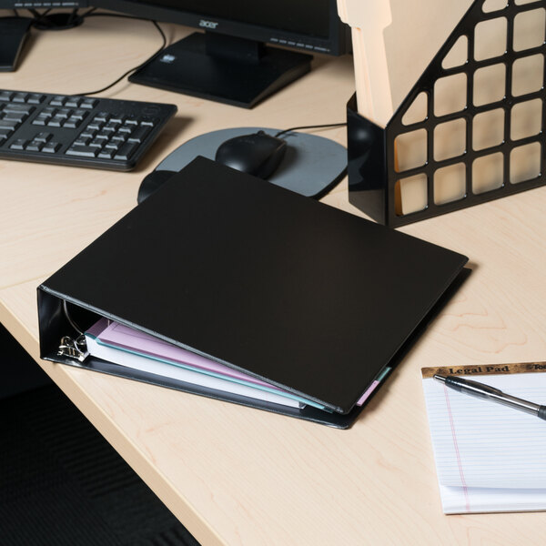 A black Universal non-view binder on a desk with a pen and papers.