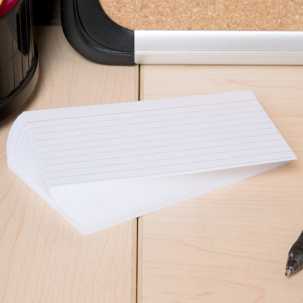 A Universal white ruled index card with a pen on a table.