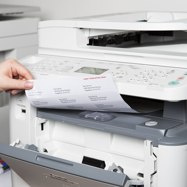 A person putting a piece of white paper with Universal UNV80102 labels into a printer.