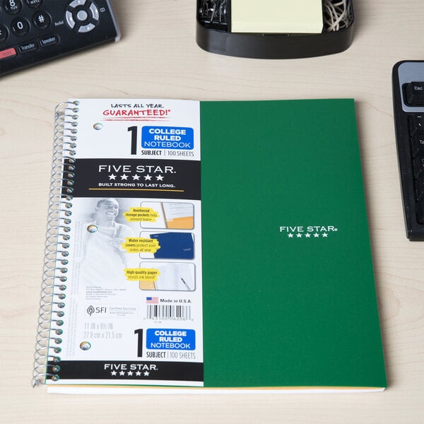 A green Five Star spiral bound notebook on a desk.