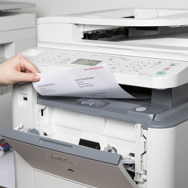 A hand putting a Universal White Permanent Label into a printer.