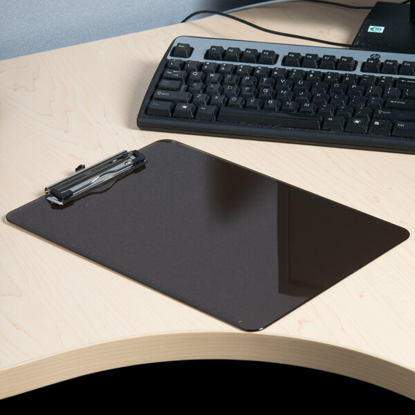 A Universal translucent black plastic clipboard on a desk next to a keyboard.