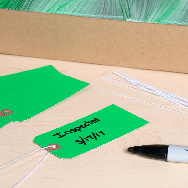 A box of green Avery shipping tags with black writing on them.