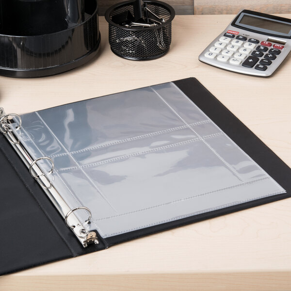 A binder with Avery 3-hole punched photo storage pages on a table with a calculator.