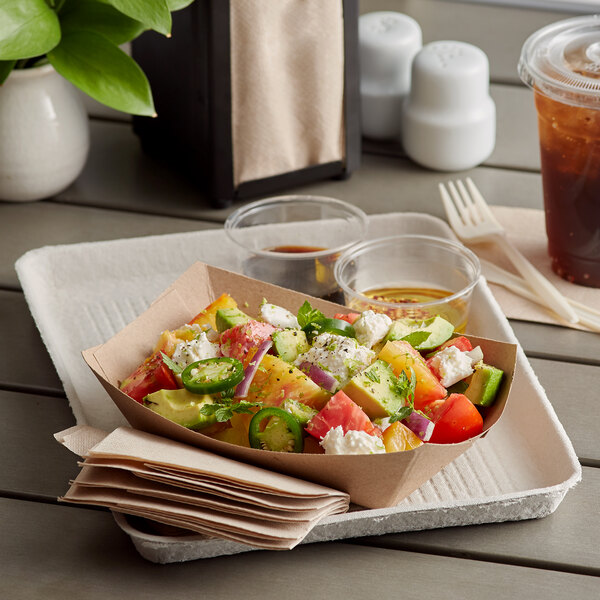 A Huhtamaki Chinet rectangular paper food tray with a salad, tomatoes, cucumbers, and other vegetables.