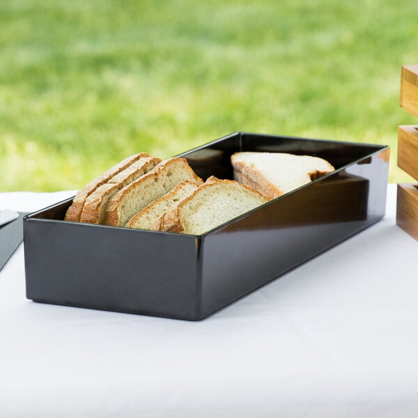 A black Cal-Mil melamine box with sliced bread on a table.