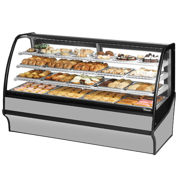 A True stainless steel curved glass dry bakery display case filled with pastries.