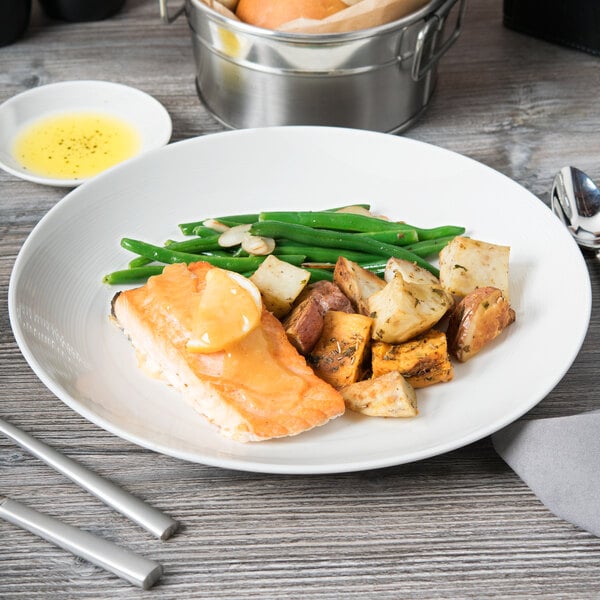 A Reserve by Libbey Royal Rideau white porcelain coupe plate with salmon, potatoes, and green beans on a table.