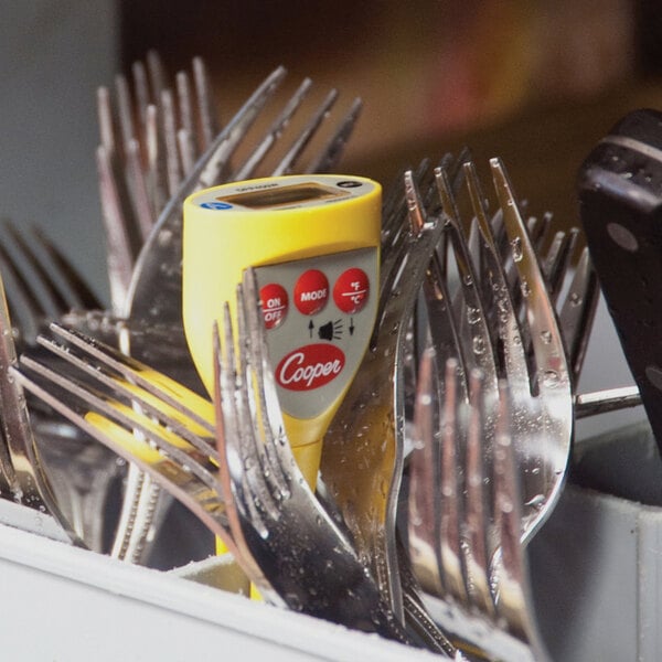 A Cooper-Atkins digital pocket probe thermometer inserted into a container of forks.