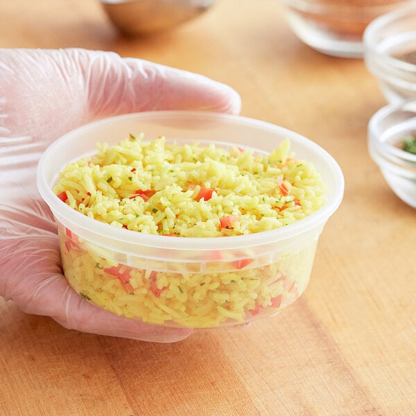 A hand holding a ChoiceHD plastic deli container of rice.