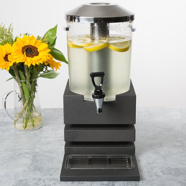 A Vollrath plastic beverage dispenser assembly with lemons in it on a counter.