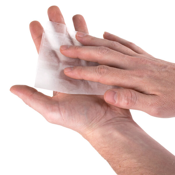 A person using a Medi-First antiseptic wipe to clean their hands.