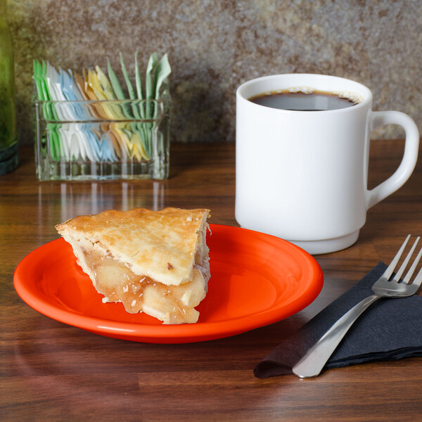 An orange Fiesta appetizer plate with a slice of pie on it next to a white mug of coffee.