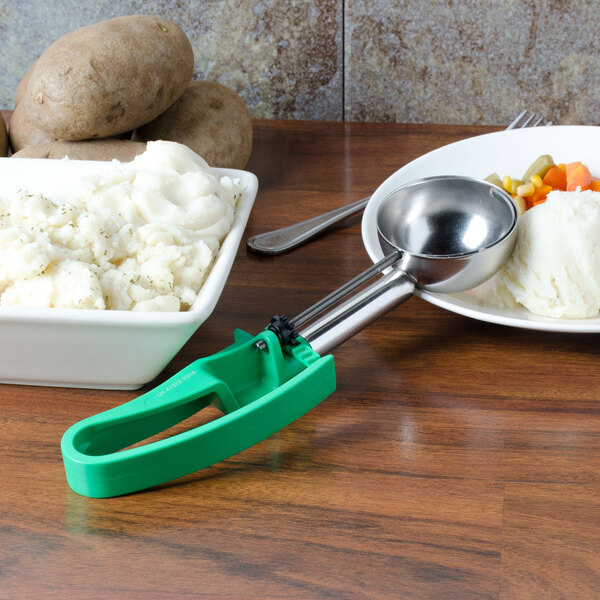 A bowl of mashed potatoes with a green Vollrath Jacob's Pride extended length scoop.