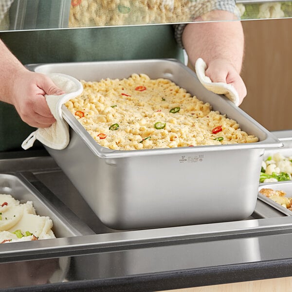 A person holding a stainless steel tray of food.