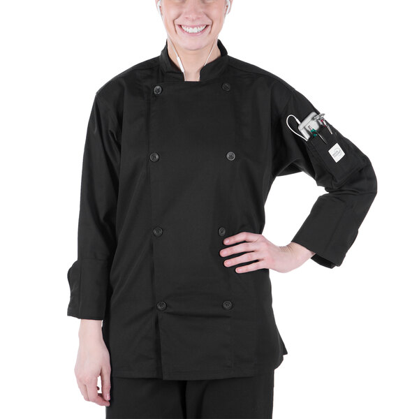 A woman wearing a black Mercer Culinary long sleeve chef jacket.