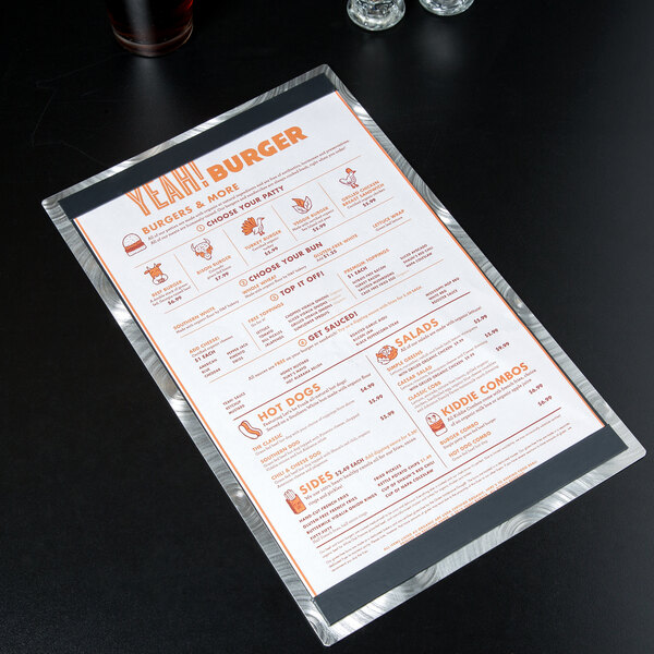 A Menu Solutions Alumitique aluminum menu board on a table with a glass of wine.
