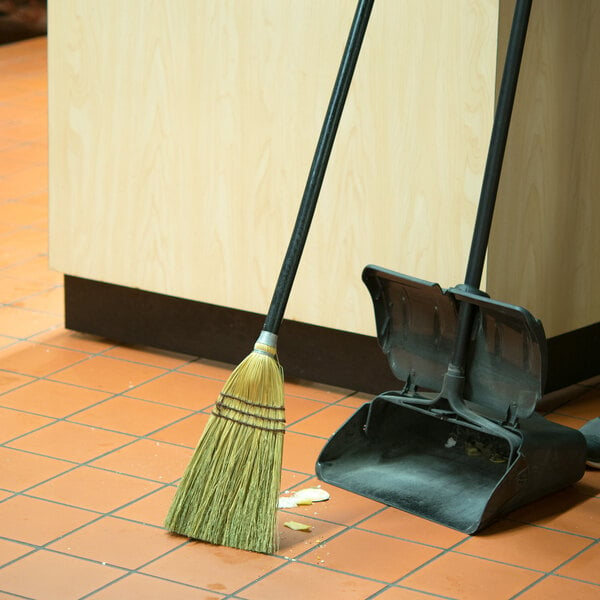 A Rubbermaid commercial broom and dustpan on the floor.