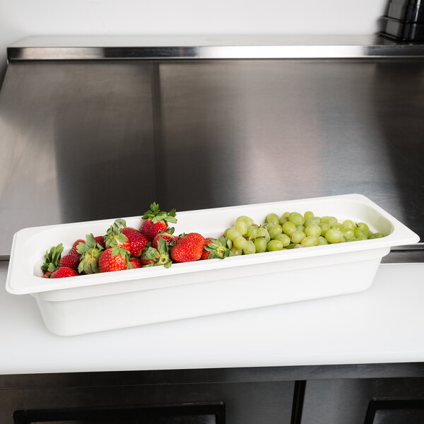 A white Cambro food pan filled with strawberries and grapes.