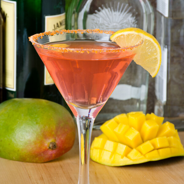 A glass of pink liquid rimmed with Rokz Mango Cocktail Sugar with a slice of mango on the rim.