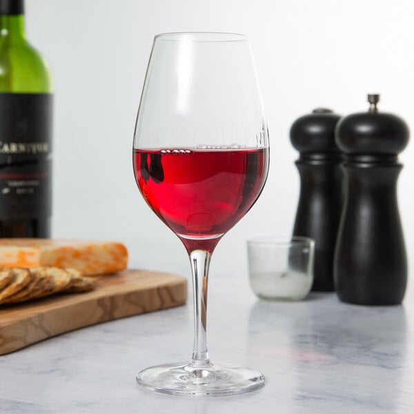 A Stolzle Celebration wine glass filled with red wine sits on a table.