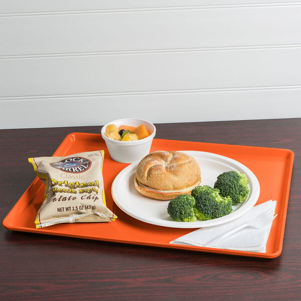 A Cambro orange pizazz dietary tray with a sandwich, broccoli, and a drink on it.