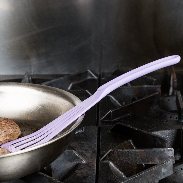 A purple Mercer Culinary allergen-free slotted turner in a pan with a burger.